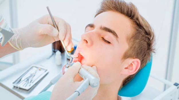 Young man receiving a root canal in Guildford from a dentist using specialized tools