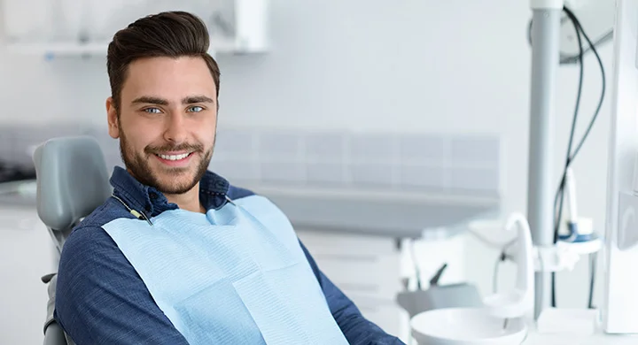 A smiling man in a dental chair at a modern clinic, representing dental services in Guildford, BC.